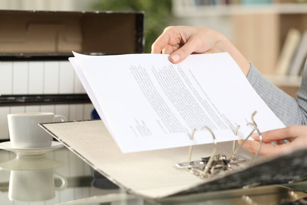 Close up of girl hands putting documents on a ring binder at home