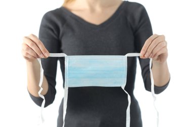 Kadın ellerine yakından bakınca, beyaz arka planda izole edilmiş kovid 19 'dan kaçınmak için cerrahi koruyucu maske görünüyor.