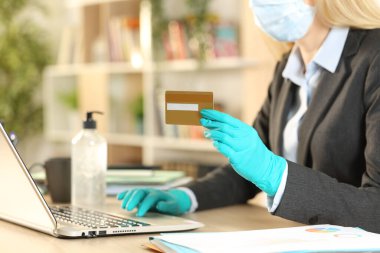 Girişimci kadının internette kredi kartıyla ödeme yapmasını ve merkez büroda maske ve eldivenlerle koronavirüsten kaçınmasını kapatın.