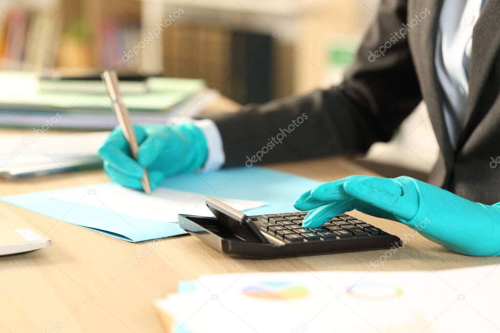 Close up of bookkeeper hands calculating bank check with calculator avoiding coronavirus with latex gloves sitting at homeoffice