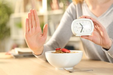 Close up of woman hands on intermittent fasting doing stop sign waiting before eating cereal bowl on a table at home clipart