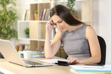 Endişeli muhasebeci kadın hesap makinesiyle hesaplama yapıyor.