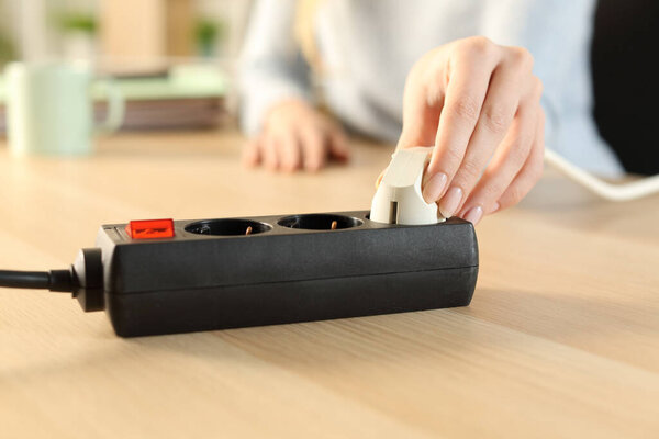 Close up of woman hand plugging plug on a power strip socket at home