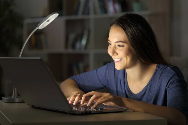 Glückliche Frau Tippt Laptop Und Sitzt Nachts Allein Mit Schreibtischlampe — Stockfoto