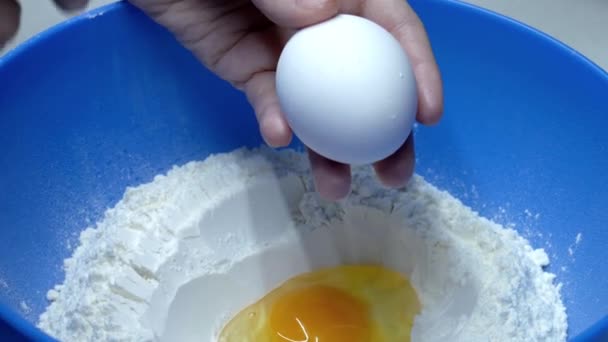 Meisje breekt een ei in een kom — Stockvideo