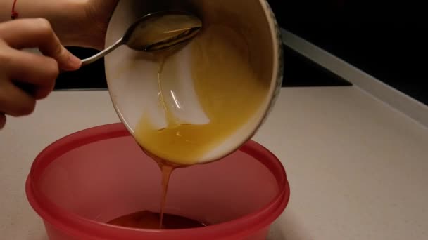 The girl pours honey into a bowl — Stock Video