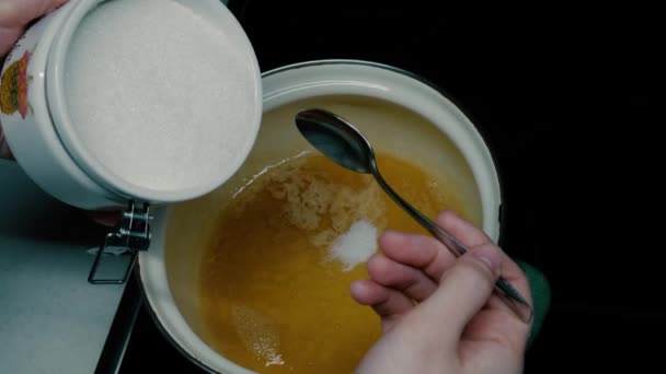 Ze giet suiker in een pan. — Stockvideo