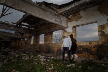 Gaz maskeli insan harabeler ve dramatik gökyüzü arkaplanı arasında duruyor. Çevresel kirlilik, ekoloji felaketi, radyasyon, biyolojik tehlike kavramı.