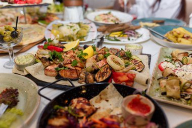 Izgara et ve sebzeli şölen yemekleri, domates, limon, sebze salatası, maydanozla süslenmiş zeytinler. Düğün ya da doğum günü sofrası. Restoranda ya da kafede ziyafet.