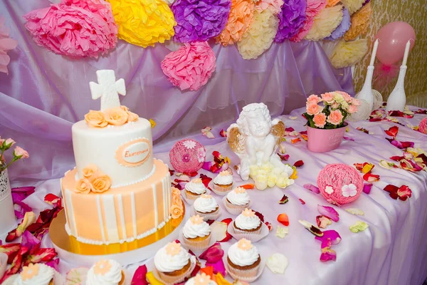 洗礼糖 天使雕像 杯子蛋糕 无精打采的蛋糕 蛋糕上的乳酪十字架 用来为孩子们的聚会洗礼 桌上有白色的蜡烛和花瓣 — 图库照片