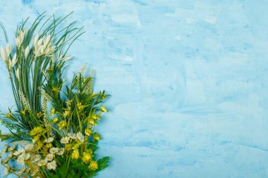 Mavi üzerine yapay sarı ve beyaz çiçekler boyanmış ahşap zemin. Bahar çiçekleri, Paskalya, kadınlar günü, anneler günü, 8 Mart konsepti. Boşluğu kopyala.