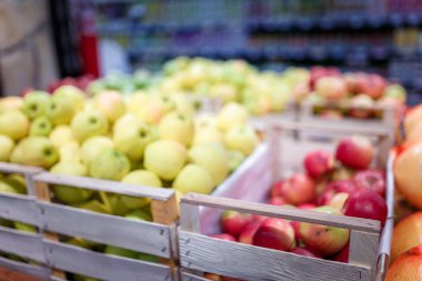 Marketteki, süpermarketteki, alışveriş merkezindeki, hipermarketteki ya da alışveriş merkezindeki meyve reyonunun yumuşak odaklı görüntüsü. Kırmızı, sarı ve yeşil elmalar kutularda. Sağlıklı beslenme, avitaminoz konsepti. 