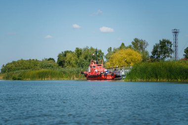 Vilkovo, Ukrayna - Ağustos 2019. Yeşil arka planda nehir lastikleri olan kırmızı motorlu tekne..