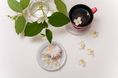 Bir fincan yasemin çayı. Beyaz masa arka planında çiçekler. Sağlıklı içecekler, bahar çiçeği konsepti.. 