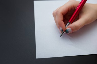 Köknar ağacı manikürlü kadın eller siyah arka plandaki beyaz kağıdın üzerinde kırmızı kalem tutuyorlar. Noel ya da kış tırnak sanatı. El bakımı, tırnak tasarımı, güzellik ve sağlık konsepti. Boşluğu kopyala.