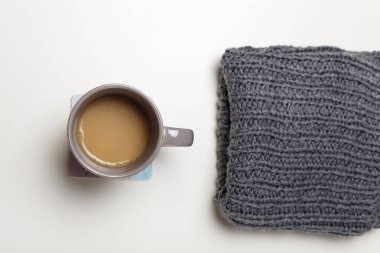 Beyaz masa arkasında bir fincan sıcak kahve ya da kakao ve gri örgü eşarp. Sıcak sonbahar ya da kış, sıcak içecekler, ev yapımı içecek konsepti..