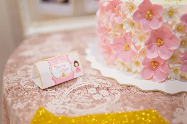 带有题词的粉色信封的软而集中的照片 Zlata只有一岁大 用奶油花和金色珠子装饰桌布和蛋糕 女孩的第一个生日聚会 — 图库照片
