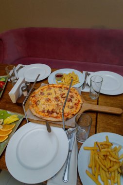 Pizza ve kızarmış patates beyaz tabakta. Kutlama masası. Sağlıksız gıda konsepti.