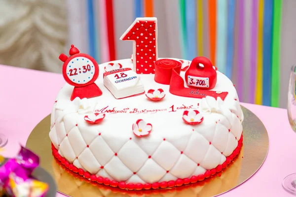 Girlish white and red cake with date and time of birth, weight and height, number 1 candle. One year old first birthday party. Inscription - Dear Victoria is 1 year old.