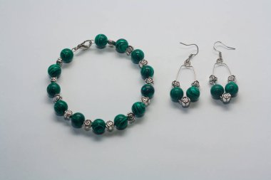 Beyaz arka planda küpe ve bilezik. Kadın aksesuarları, dekoratif süsler ve mücevherler. Moda ve tarz kavramı.