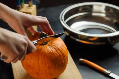 Kesme tahtasında balkabağı doğrayan bıçaklı kadın eller. Sonbahar sebzeleri hazırlanıyor. Sağlıklı organik vejetaryen gıda konsepti. 