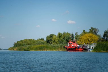 Vilkovo, Ukrayna - Ağustos 2019. Yeşil arka planda nehir lastikleri olan kırmızı motorlu tekne..