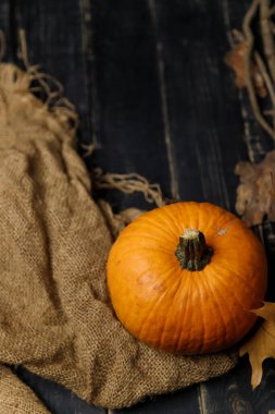 Kuru sonbahar yapraklı balkabağı, otlar ve siyah ahşap arka planda çuval bezi. Sonbahar hasadı, sağlıklı organik gıda konsepti. Boşluğu kopyala.