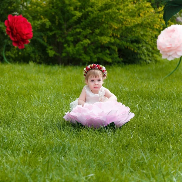Dziewczynka Białej Sukience Bawiąca Się Zielonym Trawniku Wysokimi Sztucznymi Kwiatami — Zdjęcie stockowe
