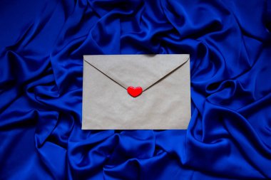 Mavi arka planda kalbi olan kağıt bir zarf.