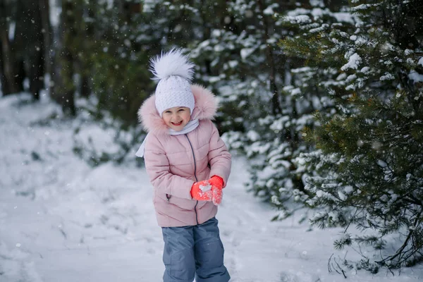 Маленькая девочка играет в снежки на улице зимой — стоковое фото