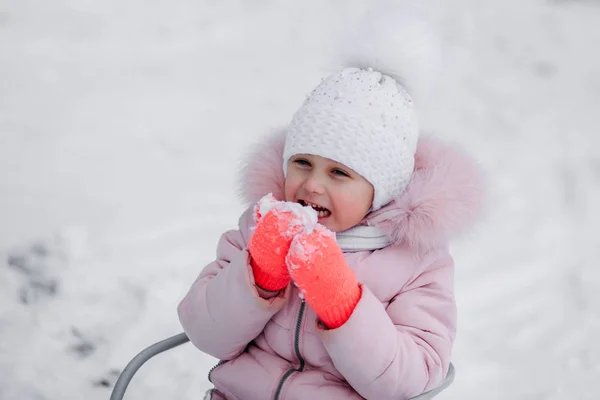 Маленькая девочка зимой ест снег на природе — стоковое фото