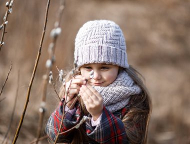 İlkbaharda ormandaki küçük tatlı kız bitkilere bakıyor.