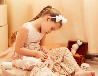 Küçük tatlı kız evde dikiş dikmekle meşgul.