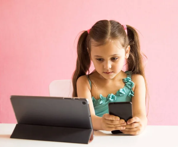 Liten Söt Flicka Med Telefon Och Tablett Vid Bordet — Stockfoto