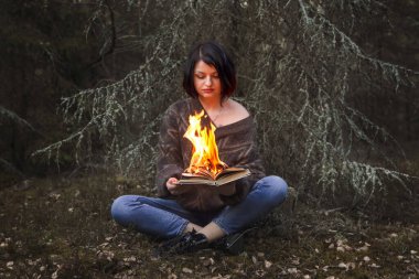 Kitap doğadaki bir kadının ellerinde yanıyor.
