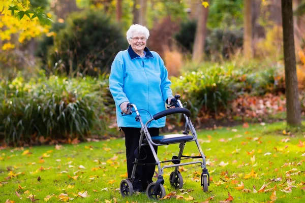 Äldre dam med en rullator i höst park — Stockfoto