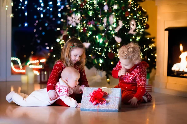 Kids opening Christmas presents at fireplace — Stock Photo, Image