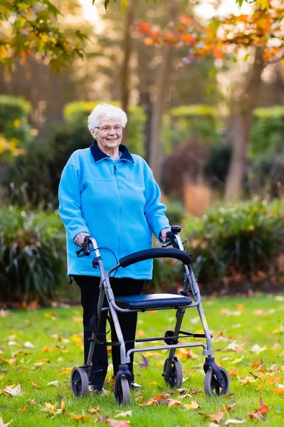 Äldre dam med en rullator i höst park — Stockfoto