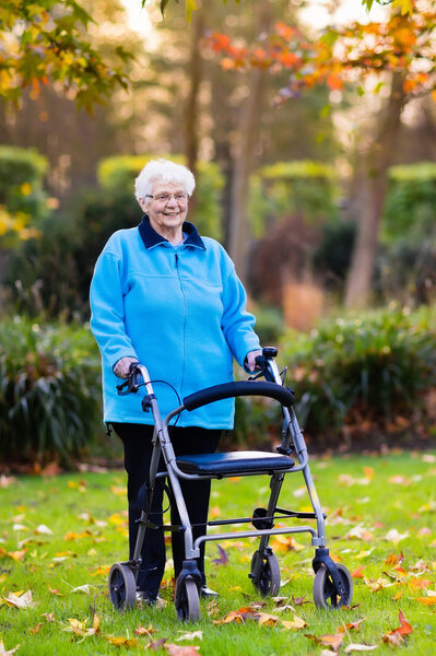 Старшая леди с ходунком в осеннем парке
