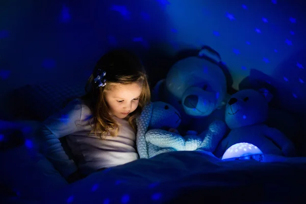 Petite fille au lit avec lampe de nuit — Photo