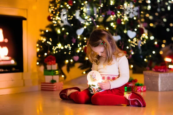 Ragazzina che tiene la palla di neve sotto l'albero di Natale — Foto Stock