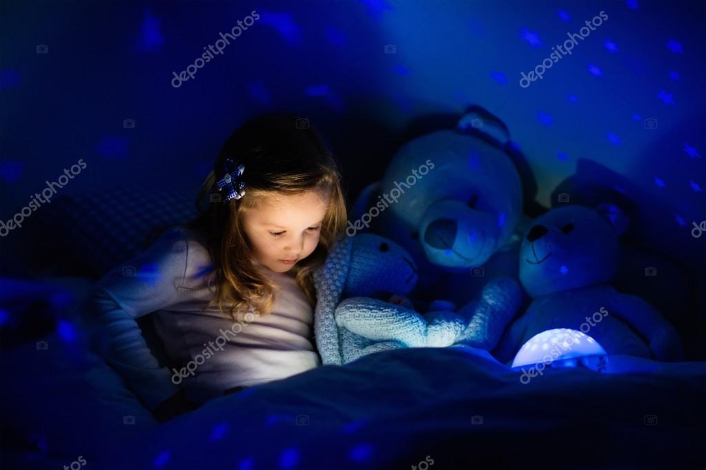 Little Girl In Bed With Night Lamp Stock Photo