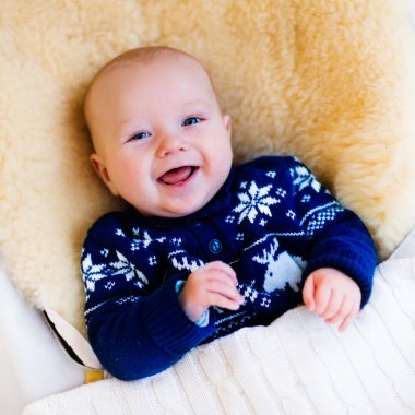 Little baby in nordic sweater on sheepskin muff