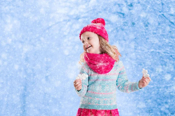 Meisje spelen met speelgoed sneeuwvlokken in winter park — Stockfoto