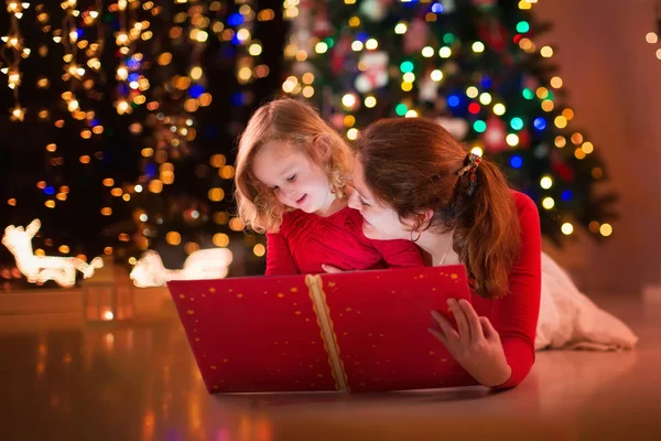 Madre e hija leyendo en la chimenea en Nochebuena —  Fotos de Stock
