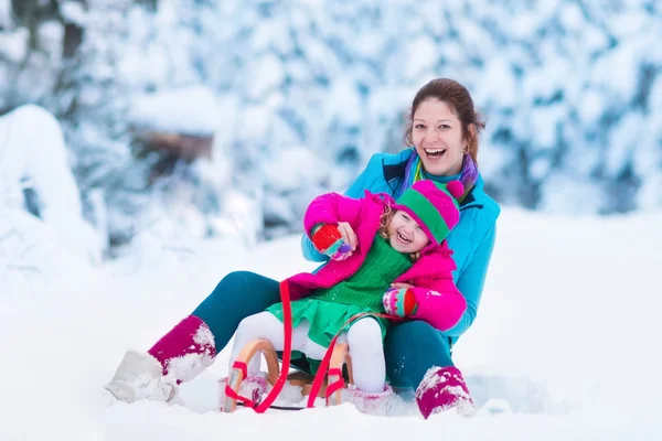 Moeder en kind rodelen in een besneeuwde park — Stockfoto