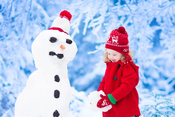 Niña construyendo un muñeco de nieve en invierno — Foto de Stock