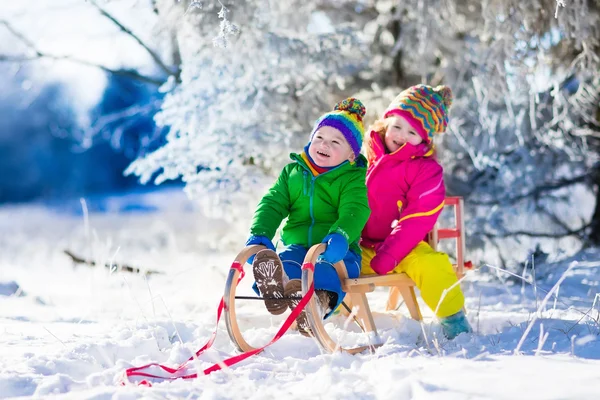 Kinder fahren Schlitten im verschneiten Winterpark — Stockfoto