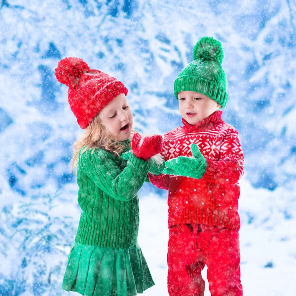 Děti hrají v zasněženém zimním lese — Stock fotografie