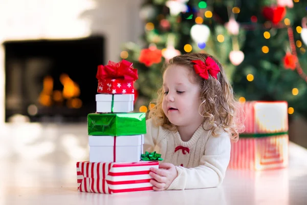 Liten flicka öppning presenterar på juldagens morgon — Stockfoto